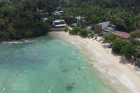 Aerial view of a turquoise bay with surfers on Sri Lanka's coast